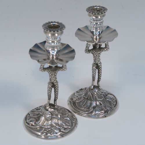 A very unusual pair of cast Sterling Silver Harlequin candlesticks, having round nozzles with drip pans, Harlequin model shaped columns, and sitting on hand-chased floral and scroll bases. These unique cast silver candlesticks were made by A. Haviland-Nye of London in 1979. The dimensions of this fine pair of hand-made cast Harlequin model sterling silver table candlesticks are height 13 cms (5 inches), the bases are 6.5 cms (2.5 inches) in diameter, and the total weight is 298g (9.6 troy ounces).   