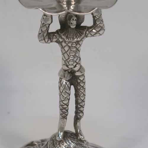 A very unusual pair of cast Sterling Silver Harlequin candlesticks, having round nozzles with drip pans, Harlequin model shaped columns, and sitting on hand-chased floral and scroll bases. These unique cast silver candlesticks were made by A. Haviland-Nye of London in 1979. The dimensions of this fine pair of hand-made cast Harlequin model sterling silver table candlesticks are height 13 cms (5 inches), the bases are 6.5 cms (2.5 inches) in diameter, and the total weight is 298g (9.6 troy ounces).