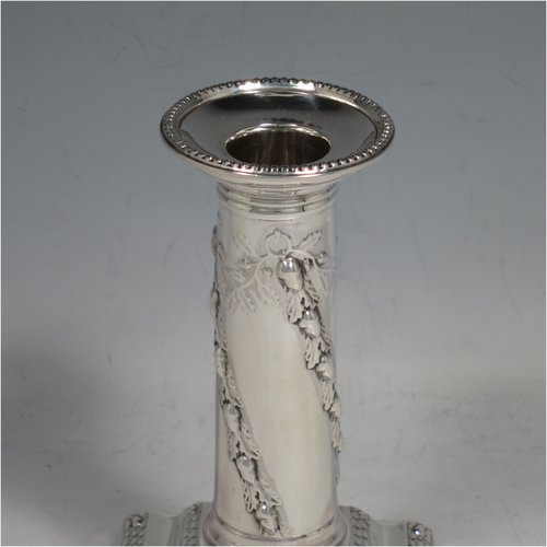 An Antique Edwardian Sterling silver pair of candlesticks, in a Neoclassical style with bead- edged borders, having straight round columns with hand-chased oak leaves and acorns, sitting on stepped bases, and with removable nozzles. Made by Thomas Bradbury of London in 1896. The dimensions of this fine pair of hand-made silver candlesticks are height 13 cms (5.25 inches), and the bases are 8 cms (3 inches) square.   