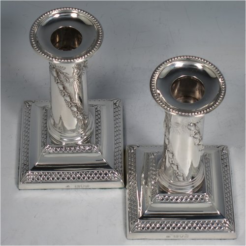 An Antique Edwardian Sterling silver pair of candlesticks, in a Neoclassical style with bead- edged borders, having straight round columns with hand-chased oak leaves and acorns, sitting on stepped bases, and with removable nozzles. Made by Thomas Bradbury of London in 1896. The dimensions of this fine pair of hand-made silver candlesticks are height 13 cms (5.25 inches), and the bases are 8 cms (3 inches) square.   