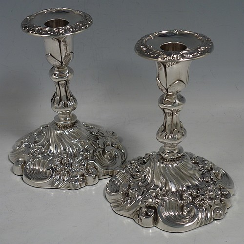 An Antique Edwardian Sterling Silver very pretty pair of candlesticks, having round baluster bodies with hand-chased floral & fluted decoration, and removable nozzles. Made by Williams Ltd., of Birmingham in 1906. The dimensions of these fine hand-made antique silver candlesticks are height 14 cms (5.5 inches), and the bases are 11 cms (4.3 inches) in diameter.    