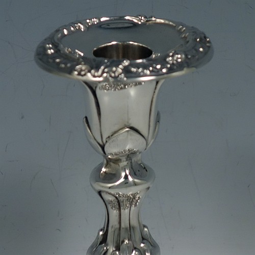 An Antique Edwardian Sterling Silver very pretty pair of candlesticks, having round baluster bodies with hand-chased floral & fluted decoration, and removable nozzles. Made by Williams Ltd., of Birmingham in 1906. The dimensions of these fine hand-made antique silver candlesticks are height 14 cms (5.5 inches), and the bases are 11 cms (4.3 inches) in diameter.