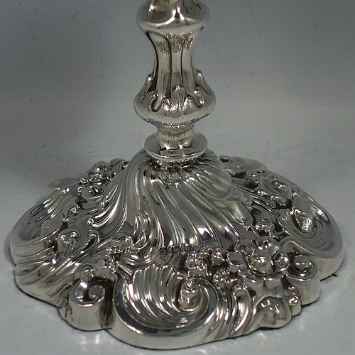 An Antique Edwardian Sterling Silver very pretty pair of candlesticks, having round baluster bodies with hand-chased floral & fluted decoration, and removable nozzles. Made by Williams Ltd., of Birmingham in 1906. The dimensions of these fine hand-made antique silver candlesticks are height 14 cms (5.5 inches), and the bases are 11 cms (4.3 inches) in diameter.