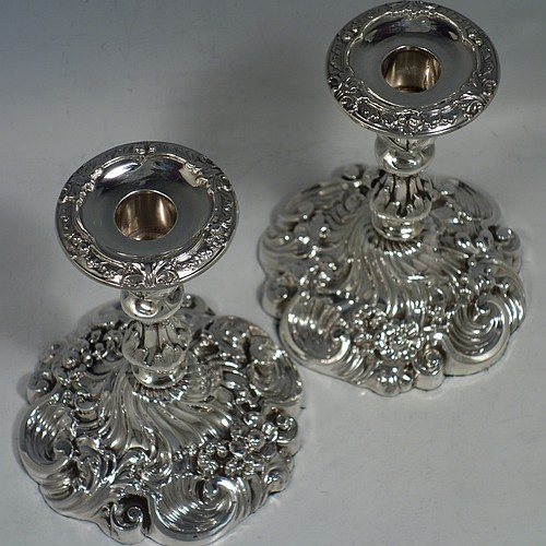 An Antique Edwardian Sterling Silver very pretty pair of candlesticks, having round baluster bodies with hand-chased floral & fluted decoration, and removable nozzles. Made by Williams Ltd., of Birmingham in 1906. The dimensions of these fine hand-made antique silver candlesticks are height 14 cms (5.5 inches), and the bases are 11 cms (4.3 inches) in diameter.