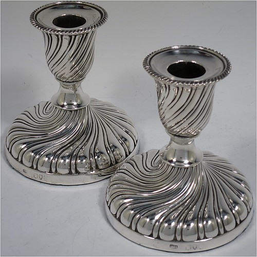 A very pretty Antique Victorian Sterling Silver pair of small candlesticks, having round bodies with hand-chased swirl-fluted decoration, and removable nozzles with applied gadroon borders. Made by Henry Holland of London in 1895. The dimensions of these fine hand-made antique silver candlesticks are height 10 cms (4 inches), and the bases are 9 cms (3.5 inches) in diameter.    