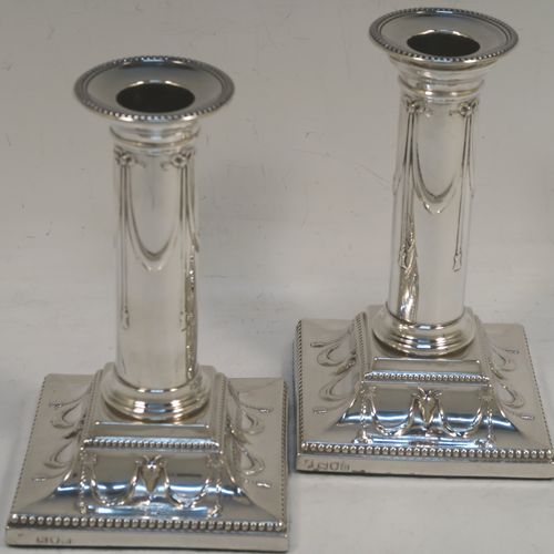 A very pretty Antique Victorian Sterling Silver pair of candlesticks, in a Neoclassical style with hand-chased bows, swags and rams heads, with bead-edged borders, round removable nozzles, and square  bases. This beautiful pair of antique silver candlesticks were made by William Gibson and John Langman (Goldsmiths and Silversmiths) of London in 1897. The dimensions of this fine pair of hand-made antique silver candlesticks are height 14 cms (5.5 inches), and the bases are 9 cms (3.5 inches) square.   
