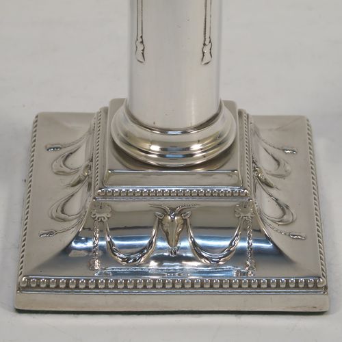 A very pretty Antique Victorian Sterling Silver pair of candlesticks, in a Neoclassical style with hand-chased bows, swags and rams heads, with bead-edged borders, round removable nozzles, and square bases. This beautiful pair of antique silver candlesticks were made by William Gibson and John Langman (Goldsmiths and Silversmiths) of London in 1897. The dimensions of this fine pair of hand-made antique silver candlesticks are height 14 cms (5.5 inches), and the bases are 9 cms (3.5 inches) square.