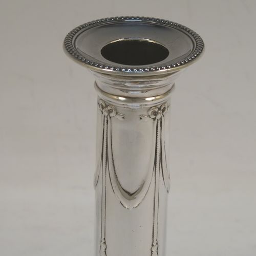 A very pretty Antique Victorian Sterling Silver pair of candlesticks, in a Neoclassical style with hand-chased bows, swags and rams heads, with bead-edged borders, round removable nozzles, and square bases. This beautiful pair of antique silver candlesticks were made by William Gibson and John Langman (Goldsmiths and Silversmiths) of London in 1897. The dimensions of this fine pair of hand-made antique silver candlesticks are height 14 cms (5.5 inches), and the bases are 9 cms (3.5 inches) square.
