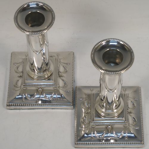 A very pretty Antique Victorian Sterling Silver pair of candlesticks, in a Neoclassical style with hand-chased bows, swags and rams heads, with bead-edged borders, round removable nozzles, and square bases. This beautiful pair of antique silver candlesticks were made by William Gibson and John Langman (Goldsmiths and Silversmiths) of London in 1897. The dimensions of this fine pair of hand-made antique silver candlesticks are height 14 cms (5.5 inches), and the bases are 9 cms (3.5 inches) square.