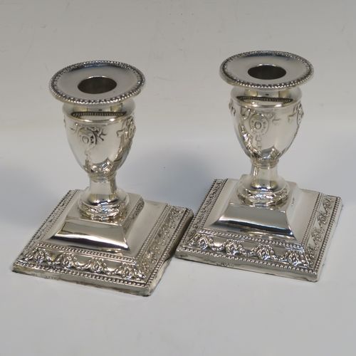 A very pretty pair of Antique Victorian Sterling Silver candlesticks, having urn-shaped bodies sitting on square pedestal bases, with hand-chased neoclassical style decoration, bead-edged borders, and removable nozzles. These beautiful antique silver candlesticks were made by Charles Boyton of London in 1892. The dimensions of these fine hand-made silver candlesticks are height 11 cms (4.3 inches), and the bases are 8.5 cms (3.3 inches) square.

  