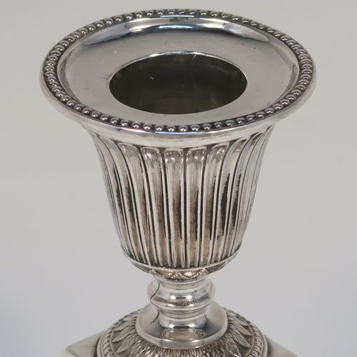 A small but very pretty pair of Antique Victorian Sterling Silver candlesticks, having urn-shaped bodies with fluted and anthemion leaf decoration, with applied bead-edged borders, sitting on square bases, and original removable nozzles. These beautiful silver candlesticks were made by Richard Hodd and Sons of London in 1877. The dimensions of these fine hand-made antique silver candlesticks are height 9 cms (3.5 inches), and the bases are 7.5 cms (3 inches) square.   