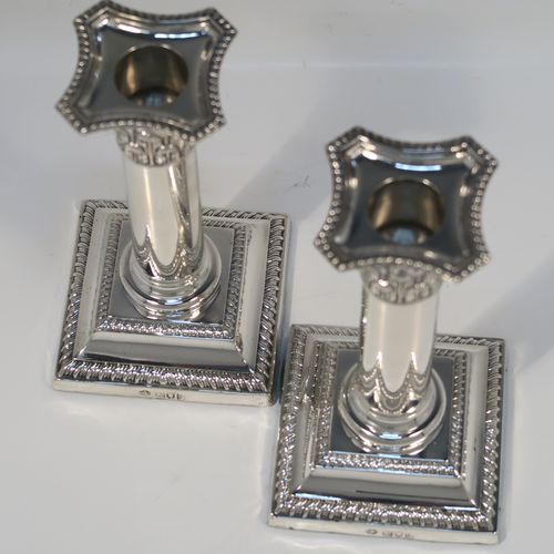 A very handsome Antique Edwardian Sterling Silver pair of candlesticks, in a Neoclassical Corinthian style, having plain round columns, and with gadroon-edged borders, removable nozzles, and square bases. This beautiful pair of antique silver candlesticks were made by William Hutton and Sons of London in 1905. The dimensions of this fine pair of hand-made antique silver candlesticks are height 14 cms (5.5 inches), and the bases are 7.5 cms (3 inches) square.   