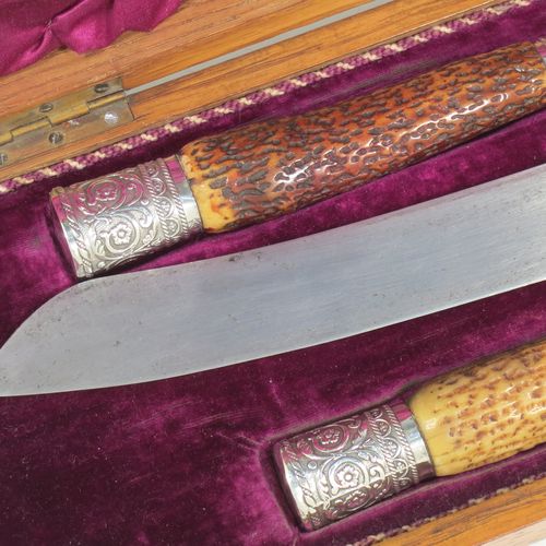 A very handsome and complete Antique Victorian Sterling Silver and deer antler horn carving set, consisting of a fork with guard, one carving knife, and one sharpening steel, with original bone antler handles and silver ferrules with hand-chased floral-work, all in their original maroon silk and velvet-lined presentation oak box. Made by Jonathan Bell of Sheffield in 1869. The dimensions of this fine hand-made antique silver and bone handled carving set are length of knife 41 cms (16 inches), length of fork 29 cms (11.5 inches), and length of steel 35 cms (13.75 inches).