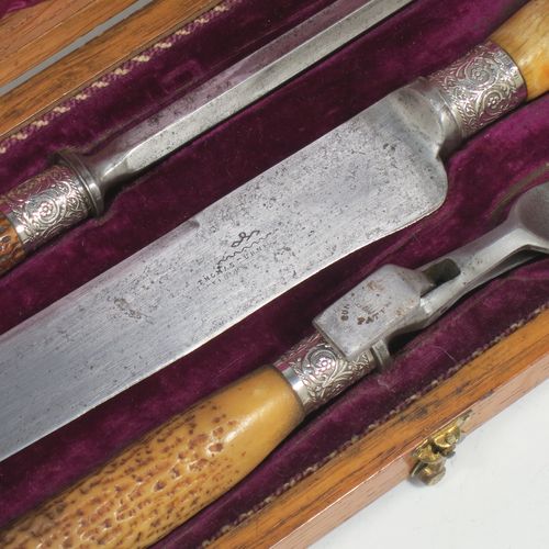 A very handsome and complete Antique Victorian Sterling Silver and deer antler horn carving set, consisting of a fork with guard, one carving knife, and one sharpening steel, with original bone antler handles and silver ferrules with hand-chased floral-work, all in their original maroon silk and velvet-lined presentation oak box. Made by Jonathan Bell of Sheffield in 1869. The dimensions of this fine hand-made antique silver and bone handled carving set are length of knife 41 cms (16 inches), length of fork 29 cms (11.5 inches), and length of steel 35 cms (13.75 inches).