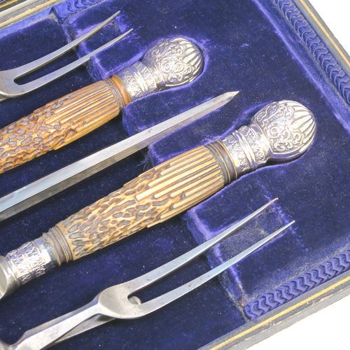 A very handsome, large, and complete Antique Victorian Sterling Silver and deer antler horn carving set, consisting of two forks with working guards, two knives, and one sharpening steel, with original bone antler handles and silver ferrules with hand-chased fluting and floral decoration, all in their original dark blue silk and velvet-lined presentation box. This fantastic original carving set was made by William Yates of Sheffield in 1899. The dimensions of this fine hand-made antique silver and bone handled carving set are length of longest knife 37 cms (14.5 inches), and length of shortest fork 27 cms (10.5 inches). Please note that the exterior of the box is slightly damaged and the lid is warped, although it does close shut properly.