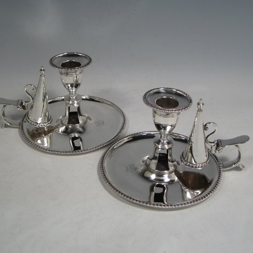 An Antique Georgian Sterling Silver pair of chamber-sticks, having plain round bodies, removable nozzles, original dunce-cap snuffers, and applied gadroon-edged borders. Made by Daniel Smith & Robert Sharp of London in 1788. The dimensions of these fine hand-made silver chambersticks are height 9 cms (3.4 inches), diameter 14 cms (5.5 inches), and they weigh a total of approx. 580g (18.7 troy ounces). Please note that both items are crested.    