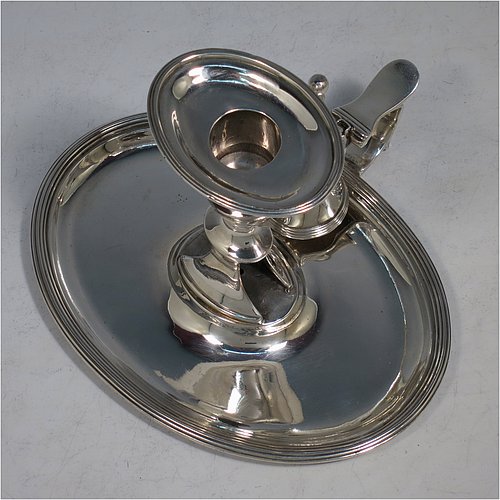 An Antique Georgian Sterling Silver chamber-stick, having an oval body, a plain scroll handle with thumb-piece, an original removable dunce-cap extinguisher, an original removable nozzle, and with applied reed-edged borders. Made by William Bennett of London in 1802. The dimensions of this fine hand-made antique silver chamberstick are width 16 cms (6.3 inches), depth 15 cms (6 inches), height 10 cms (4 inches), and it weighs approx. 319g (10.3 troy ounces).
