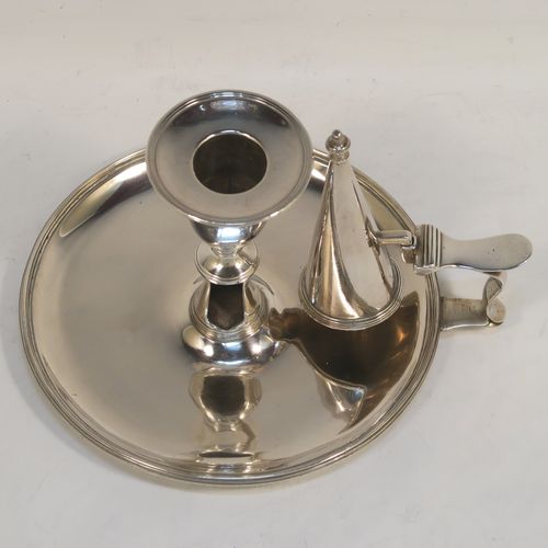 A handsome Antique Georgian Sterling Silver chamber-stick, having a round base, a scroll handle, an original removable dunce-cap extinguisher, an original removable nozzle, and with applied reed-edged borders. This beautiful antique silver chamberstick was made by John Huston of London in 1789. The dimensions of this fine hand-made silver chamberstick are diameter 14 cms (5.5 inches), height 9 cms (3.5 inches), and it weighs approx. 283g (9 troy ounces).