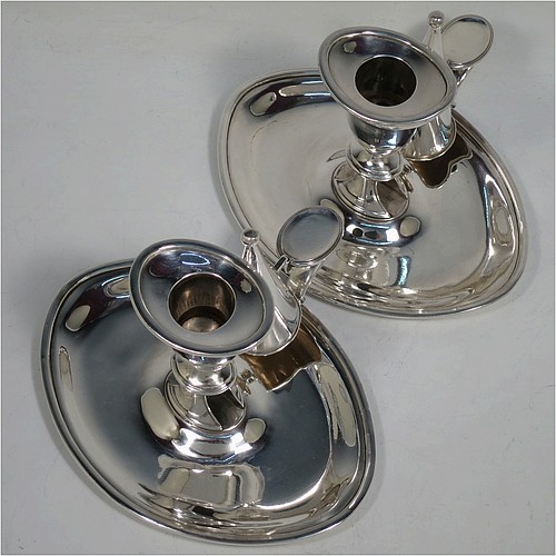 A very handsome pair of Antique Georgian Sterling Silver chamber-sticks, having plain oval bodies, scroll handles with thumb-pieces, original removable dunce-cap extinguishers, original removable nozzles, and with applied reed-edged borders. Made by James Ellis and Co., of Sheffield in 1795. The dimensions of these fine hand-made antique silver chambersticks are length 17 cms (6.75 inches), width 13 cms (5 inches), height 10 cms (4 inches), and they weigh a total of approx. 580g (18.7 troy ounces).