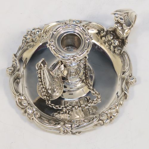 A very pretty Antique early Victorian Sterling Silver small chamber-stick for taper-stick size candles, having a round body with applied scroll and floral borders, a cast scroll handle, an original removable dunce-cap extinguisher with a security chain, and an original removable nozzle. This beautiful antique silver chamberstick was made by the Barnard Brothers of London in 1838. The dimensions of this fine hand-made silver chamberstick are diameter 9 cms (3.5 inches), height 5.5 cms (2.25 inches), and it weighs approx. 117g (3.8 troy ounces).
