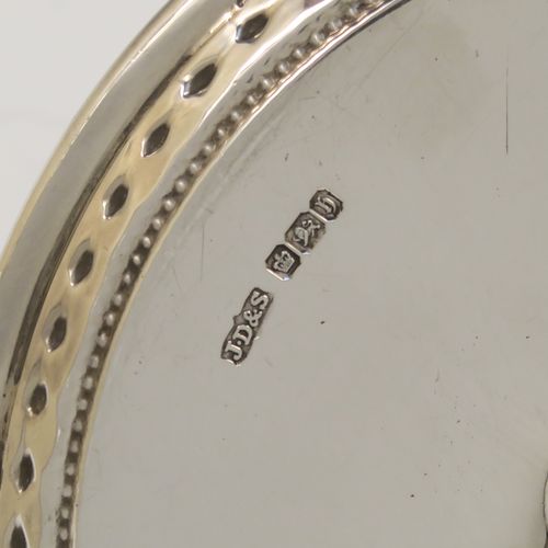 A very pretty Antique Victorian Sterling Silver chamber-stick, having a plain body with a round base, a cast plain scroll side-handle, an original removable dunce-cap extinguisher, an original removable nozzle, and with applied floral and bead-edged borders. This beautiful silver chamberstick was made by James Dixon and Sons of Sheffield of Sheffield in 1900. The dimensions of this fine hand-made antique silver chamberstick are diameter 13.5 cms (5.25 inches), height 9.5 cms (3.75 inches), and it weighs approx. 258g (8.3 troy ounces).
