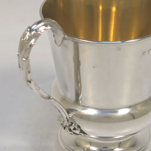 A handsome Antique Georgian Sterling Silver christening mug, having a plain round bellied body with a gold-gilt interior, an acanthus leaf scroll handle, and sitting on a pedestal foot. This elegant antique silver christening mug was made by Matthew Boulton of Birmingham in 1823. The dimensions of this fine hand-made antique silver christening mug are height 9.5 cms (3.75 inches), length 10 cms (4 inches), and it weighs approx. 128g (4 troy ounces).