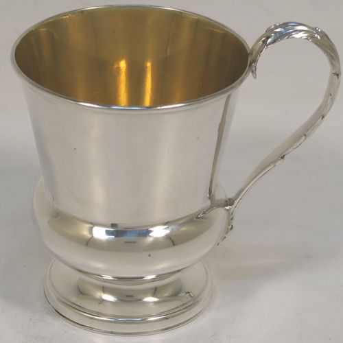 A handsome Antique Georgian Sterling Silver christening mug, having a plain round bellied body with a gold-gilt interior, an acanthus leaf scroll handle, and sitting on a pedestal foot. This elegant antique silver christening mug was made by Matthew Boulton of Birmingham in 1823. The dimensions of this fine hand-made antique silver christening mug are height 9.5 cms (3.75 inches), length 10 cms (4 inches), and it weighs approx. 128g (4 troy ounces).