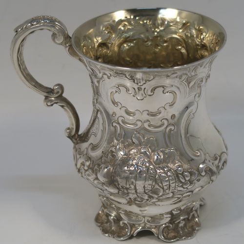 A very pretty Antique Victorian Sterling Silver christening mug, having a round bellied body with hand-chased floral and scroll-work decoration surrounding a vacant front cartouche, a cast scroll side-handle, a gold-gilt interior, and all sitting on four cast foliate feet. This beautiful antique silver christening mug was made by Martin Hall and Co., of Sheffield in 1856. The dimensions of this fine hand-made antique silver christening mug are height 11.5 cms (4.5 inches), diameter at lip 8 cms (3 inches), and it weighs approx. 163g (5.3 troy ounces).   