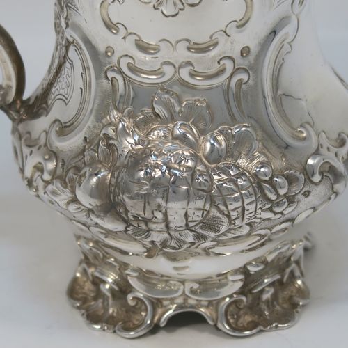 A very pretty Antique Victorian Sterling Silver christening mug, having a round bellied body with hand-chased floral and scroll-work decoration surrounding a vacant front cartouche, a cast scroll side-handle, a gold-gilt interior, and all sitting on four cast foliate feet. This beautiful antique silver christening mug was made by Martin Hall and Co., of Sheffield in 1856. The dimensions of this fine hand-made antique silver christening mug are height 11.5 cms (4.5 inches), diameter at lip 8 cms (3 inches), and it weighs approx. 163g (5.3 troy ounces).