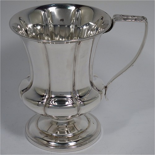 An Antique Georgian Sterling Silver christening mug, having a round bellied body, with hand-chased melon style fluted decoration, an acanthus leaf scroll handle, and sitting on a pedestal foot. Made by William Bateman of London in 1829. The dimensions of this fine hand-made antique silver christening mug are height 11 cms (4.3 inches), length 11.5 cms (4.5 inches), and it weighs approx. 185g (6 troy ounces).