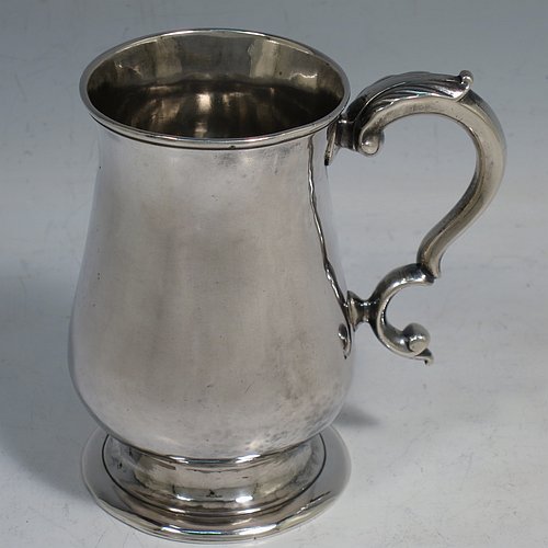 An Antique Georgian Sterling Silver christening mug, having a plain round bellied body, a scroll handle, and sitting on a collet foot. Made in London in 1774. The dimensions of this fine hand-made antique silver christening mug are height 9.5 cms (3.75 inches), diameter at top 6 cms (2.3 inches), and it weighs approx. 175g (5.6 troy ounces).