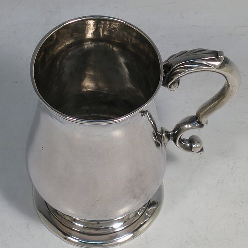 An Antique Georgian Sterling Silver christening mug, having a plain round bellied body, a scroll handle, and sitting on a collet foot. Made in London in 1774. The dimensions of this fine hand-made antique silver christening mug are height 9.5 cms (3.75 inches), diameter at top 6 cms (2.3 inches), and it weighs approx. 175g (5.6 troy ounces).