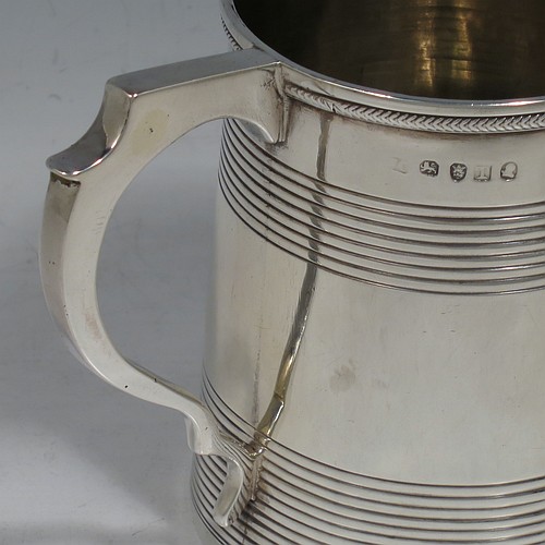 An Antique Georgian Sterling Silver christening mug, having a plain round body with two bands of hand-chased reeded decoration, an applied rope-twist top border, a scroll handle, and sitting on a flat base. Made in London in 1814. The dimensions of this fine hand-made antique silver christening mug are height 9 cms (3.5 inches), length 10 cms (4 inches), and it weighs approx. 129g (4.2 troy ounces).