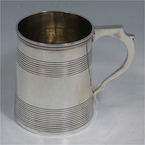 An Antique Georgian Sterling Silver christening mug, having a plain round body with two bands of hand-chased reeded decoration, an applied rope-twist top border, a scroll handle, and sitting on a flat base. Made in London in 1814. The dimensions of this fine hand-made antique silver christening mug are height 9 cms (3.5 inches), length 10 cms (4 inches), and it weighs approx. 129g (4.2 troy ounces).