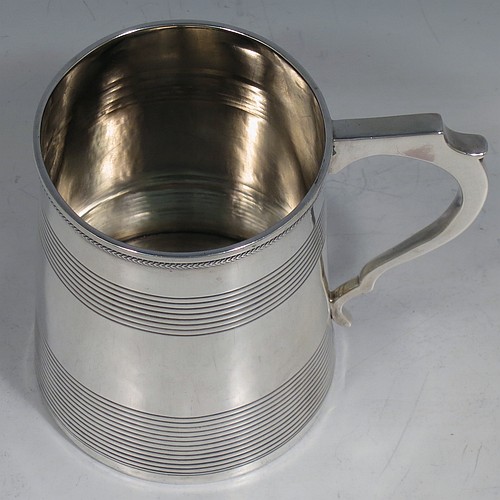An Antique Georgian Sterling Silver christening mug, having a plain round body with two bands of hand-chased reeded decoration, an applied rope-twist top border, a scroll handle, and sitting on a flat base. Made in London in 1814. The dimensions of this fine hand-made antique silver christening mug are height 9 cms (3.5 inches), length 10 cms (4 inches), and it weighs approx. 129g (4.2 troy ounces).