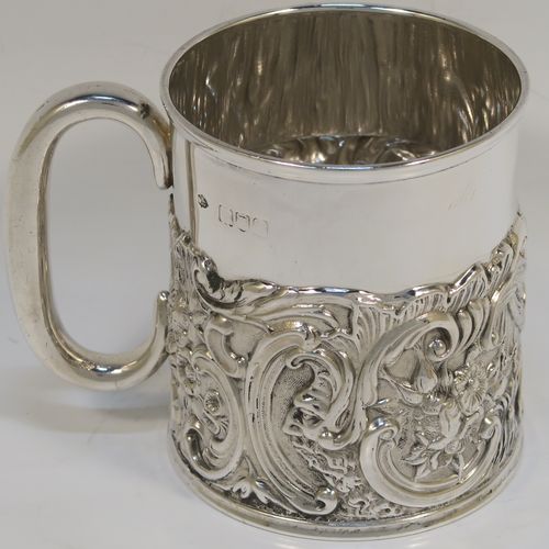 A pretty Antique Victorian Sterling Silver christening mug, having a round straight sided body with a reeded top border, a lower band of hand-chased scroll and floral decoration, a plain loop side-handle, and all sitting on a flat base. This beautiful antique silver christening mug was made by William Comyns of London in 1897. The dimensions of this fine hand-made antique silver christening mug are height 9 cms (3.5 inches), diameter at lip 7.5 cms (3 inches), and it weighs approx. 168g (5.4 troy ounces).  