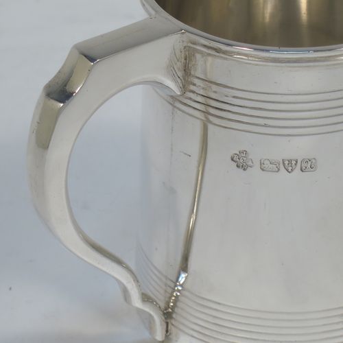 A very elegant Sterling Silver Georgian style christening mug, having a plain round body with two bands of hand-chased reeded decoration, a scroll handle with flat top, and sitting on a flat base. Made by Jays of Oxford Street, London in 1923. The dimensions of this fine hand-made silver christening mug are height 8 cms (3 inches), length 10 cms (4 inches), and it weighs approx. 160g (5.2 troy ounces).