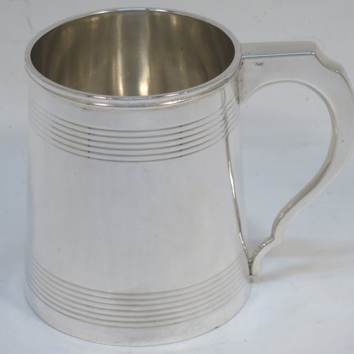 A very elegant Sterling Silver Georgian style christening mug, having a plain round body with two bands of hand-chased reeded decoration, a scroll handle with flat top, and sitting on a flat base. Made by Jays of Oxford Street, London in 1923. The dimensions of this fine hand-made silver christening mug are height 8 cms (3 inches), length 10 cms (4 inches), and it weighs approx. 160g (5.2 troy ounces).