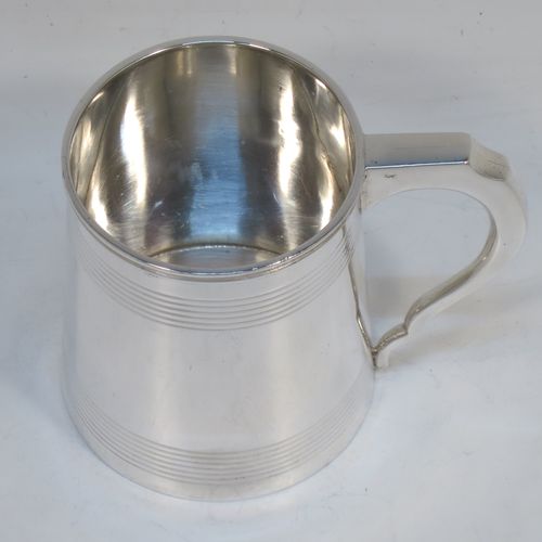 A very elegant Sterling Silver Georgian style christening mug, having a plain round body with two bands of hand-chased reeded decoration, a scroll handle with flat top, and sitting on a flat base. Made by Jays of Oxford Street, London in 1923. The dimensions of this fine hand-made silver christening mug are height 8 cms (3 inches), length 10 cms (4 inches), and it weighs approx. 160g (5.2 troy ounces).