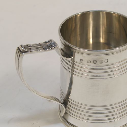 An elegant Antique Georgian Sterling Silver christening mug, having a plain round body with two bands of hand-chased reeded decoration, a scroll handle with an applied anthemion leaf thumb-piece, and sitting on a flat base. This handsome antique silver christening mug was made by Emes and Barnard in London in 1821. The dimensions of this fine hand-made antique silver christening mug are height 7.5 cms (3 inches), length 9 cms (3.5 inches), and it weighs approx. 115g (3.7 troy ounces).