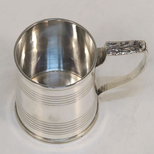 An elegant Antique Georgian Sterling Silver christening mug, having a plain round body with two bands of hand-chased reeded decoration, a scroll handle with an applied anthemion leaf thumb-piece, and sitting on a flat base. This handsome antique silver christening mug was made by Emes and Barnard in London in 1821. The dimensions of this fine hand-made antique silver christening mug are height 7.5 cms (3 inches), length 9 cms (3.5 inches), and it weighs approx. 115g (3.7 troy ounces).