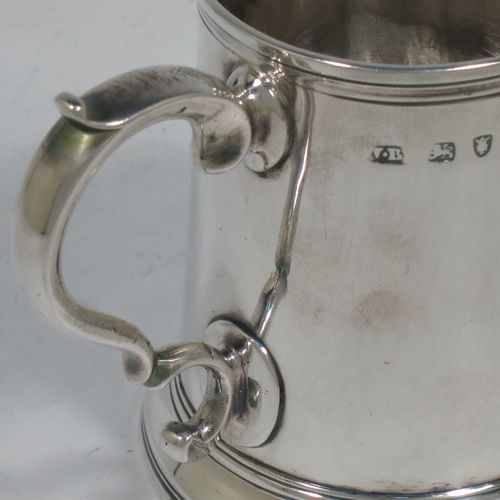 A very handsome Antique Georgian Sterling Silver christening mug, having a plain round body with applied reeded borders, a scroll handle, and sitting on a collet foot. Made by Walter Brind of London in 1770. The dimensions of this fine hand-made antique silver christening mug are height 9 cms (3.5 inches), length 11 cms (4.25 inches), and it weighs approx. 175g (5.6 troy ounces).    