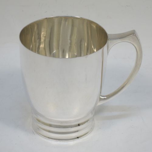 A very handsome Art Deco style Sterling Silver christening mug, having a plain round body with tapering sides, a scroll handle, and sitting on a pedestal foot with banded decoration. Made by James Dixon and Sons of Sheffield in 1938. The dimensions of this fine hand-made Art Deco silver christening mug are height 8 cms (3.25 inches), length 9 cms (3.5 inches), and it weighs approx. 165g (5.3 troy ounces).