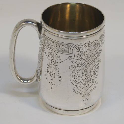 A very pretty Antique Victorian Sterling Silver christening mug, having a round body with straight tapering sides and tucked under belly, with hand-engraved floral and scroll-work decoration, a plain loop handle, a gold-gilt interior, and all sitting on a collet foot. This beautiful silver christening mug was made by George Adams of London in 1878. The dimensions of this fine hand-made antique silver christening mug are height 8 cms (3 inches), diameter at lip 5 cms (2 inches), and it weighs approx. 93g (3 troy ounces).   
