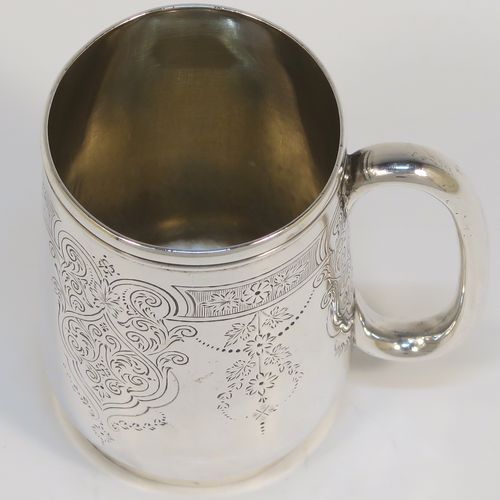 A very pretty Antique Victorian Sterling Silver christening mug, having a round body with straight tapering sides and tucked under belly, with hand-engraved floral and scroll-work decoration, a plain loop handle, a gold-gilt interior, and all sitting on a collet foot. This beautiful silver christening mug was made by George Adams of London in 1878. The dimensions of this fine hand-made antique silver christening mug are height 8 cms (3 inches), diameter at lip 5 cms (2 inches), and it weighs approx. 93g (3 troy ounces).   