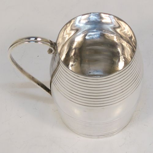 An elegant Antique Georgian Sterling Silver christening mug, having a round barrel-shaped body with two bands of hand-chased reeded decoration, a scroll side-handle, and sitting on a flat base. This handsome antique silver christening mug was made by James Jennings of London in 1780. The dimensions of this fine hand-made antique silver christening mug are height 6.5 cms (2.75 inches), length 8 cms (3 inches), and it weighs approx. 71g (2.3 troy ounces).