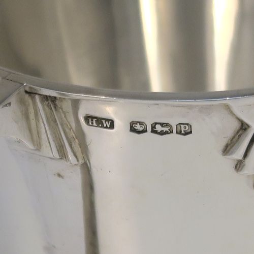 A very handsome Art Deco style Sterling Silver christening mug, having a plain round body with tapering sides, angular side handle, with four applied sunburst decals under the top rim, and sitting on a plain collet foot. This elegant silver christening mug was made by Henry Wigfall of Sheffield in 1932. The dimensions of this fine hand-made Art Deco silver christening mug are height 7 cms (2.75 inches), length 10 cms (4 inches), and it weighs approx. 109g (3.5 troy ounces).