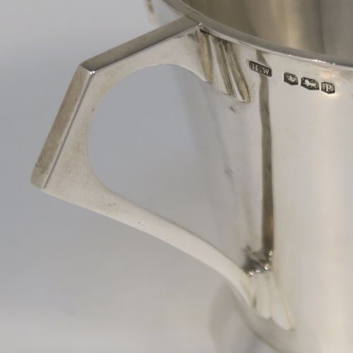 A very handsome Art Deco style Sterling Silver christening mug, having a plain round body with tapering sides, angular side handle, with four applied sunburst decals under the top rim, and sitting on a plain collet foot. This elegant silver christening mug was made by Henry Wigfall of Sheffield in 1932. The dimensions of this fine hand-made Art Deco silver christening mug are height 7 cms (2.75 inches), length 10 cms (4 inches), and it weighs approx. 109g (3.5 troy ounces).