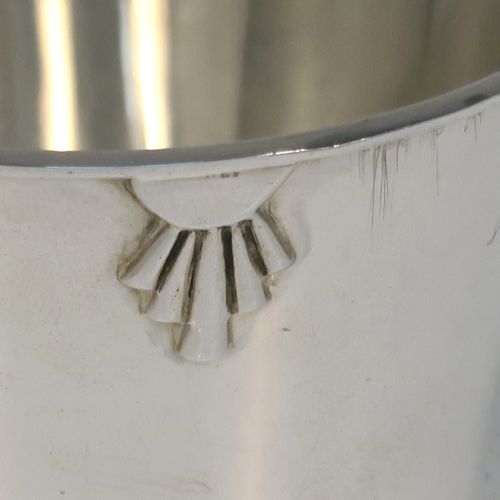 A very handsome Art Deco style Sterling Silver christening mug, having a plain round body with tapering sides, angular side handle, with four applied sunburst decals under the top rim, and sitting on a plain collet foot. This elegant silver christening mug was made by Henry Wigfall of Sheffield in 1932. The dimensions of this fine hand-made Art Deco silver christening mug are height 7 cms (2.75 inches), length 10 cms (4 inches), and it weighs approx. 109g (3.5 troy ounces).