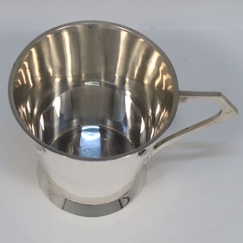 A very handsome Art Deco style Sterling Silver christening mug, having a plain round body with tapering sides, angular side handle, with four applied sunburst decals under the top rim, and sitting on a plain collet foot. This elegant silver christening mug was made by Henry Wigfall of Sheffield in 1932. The dimensions of this fine hand-made Art Deco silver christening mug are height 7 cms (2.75 inches), length 10 cms (4 inches), and it weighs approx. 109g (3.5 troy ounces).
